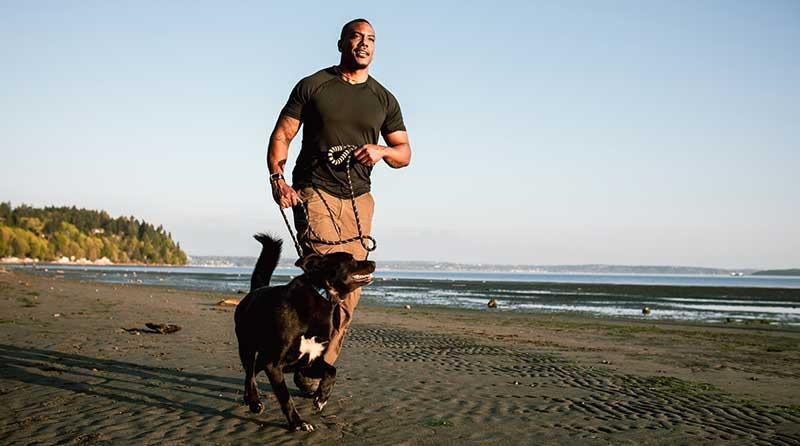 一名男子带着宠物狗在沙滩上奔跑